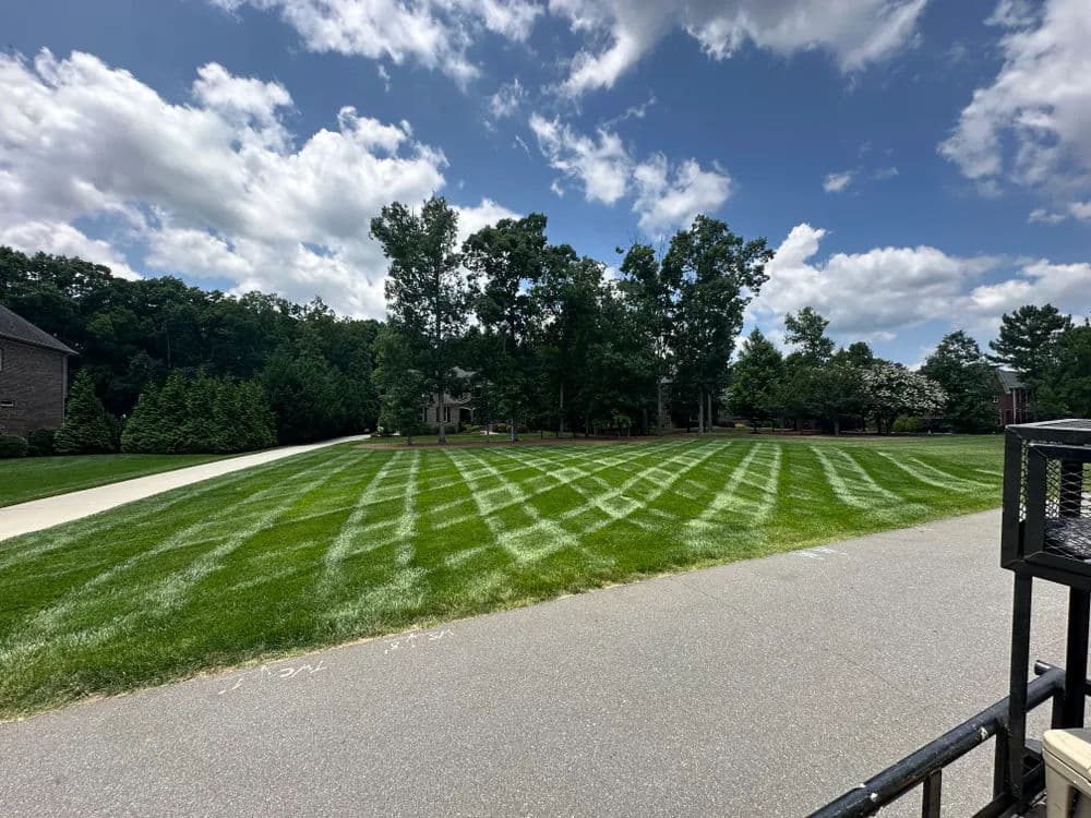 Well-manicured lawn with striped grass patterns and a cloudy sky in the background.