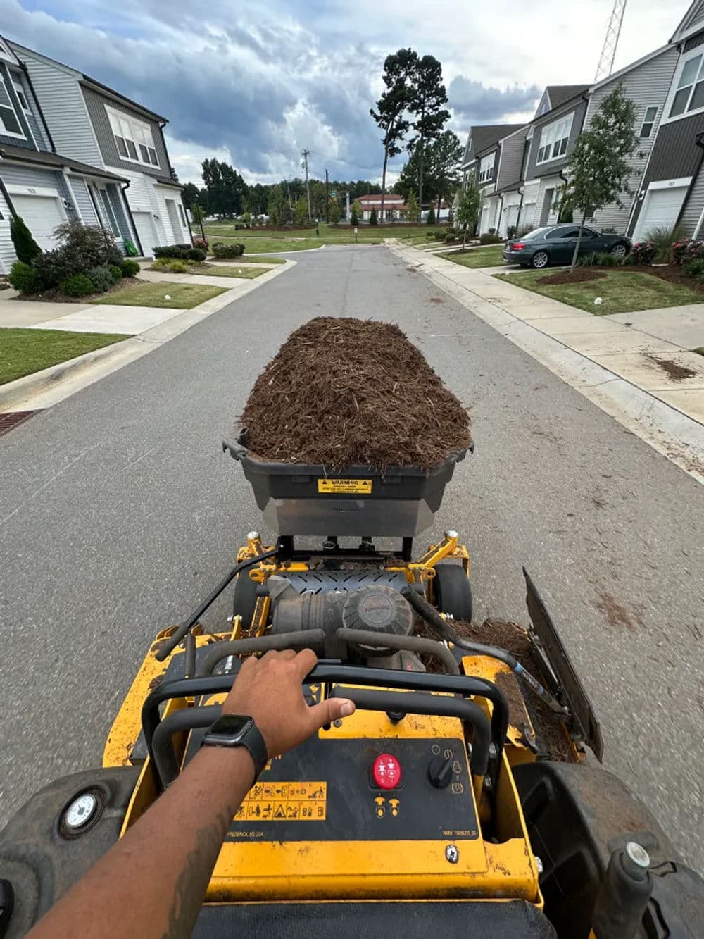 View from a landscaping machine transporting mulch on a residential street.